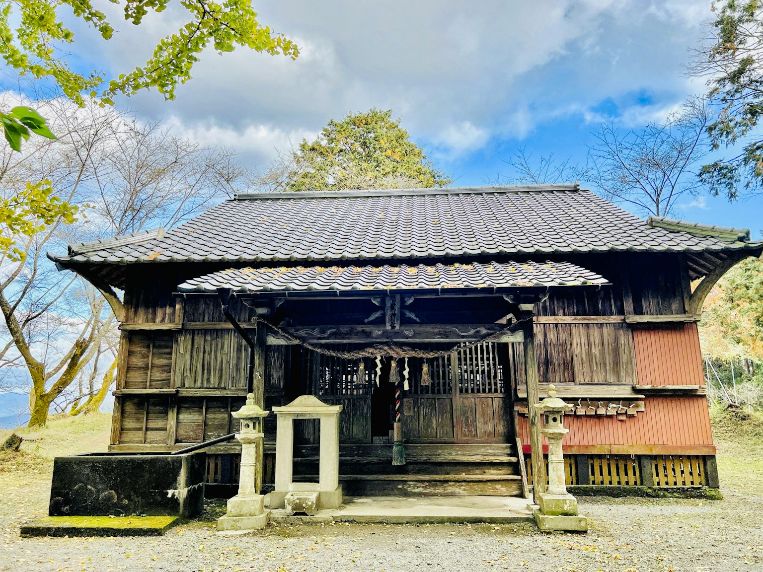 Traditional Japanese building wooden shrine with green trees and sky in the background