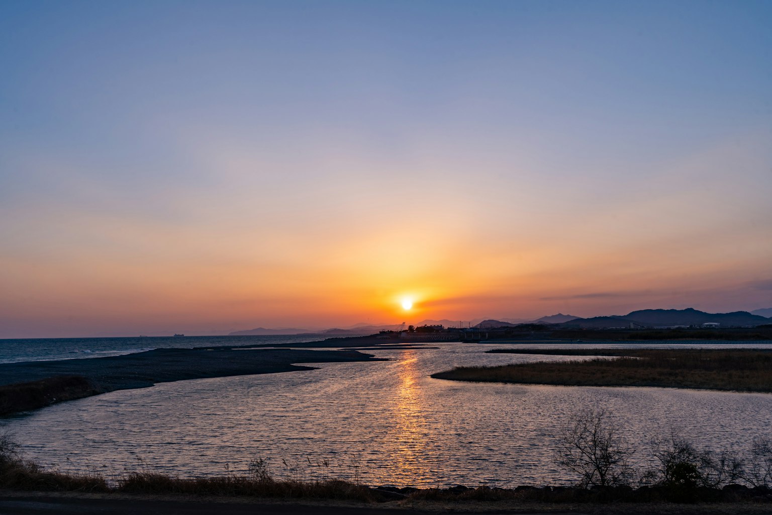 A beautiful sunset over the sea with a winding river reflecting the colors of the sky and surrounding nature