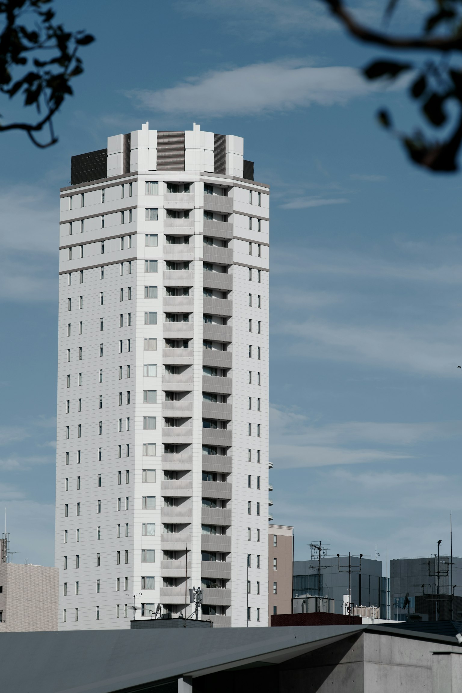 อาคารอพาร์ตเมนต์สีขาวสูงมีระเบียงท่ามกลางท้องฟ้าสีฟ้า