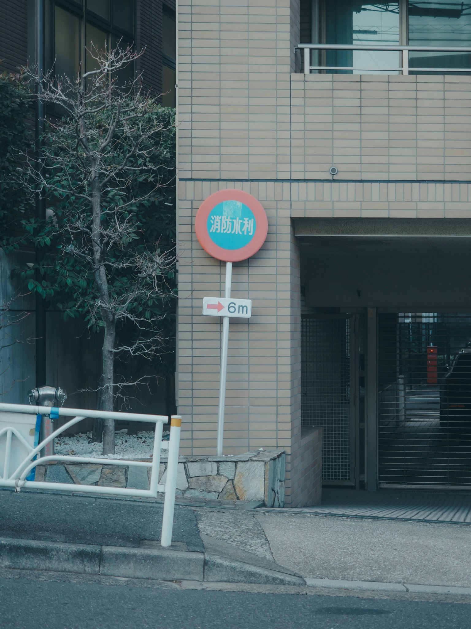 Bus stop sign near a building with a tree