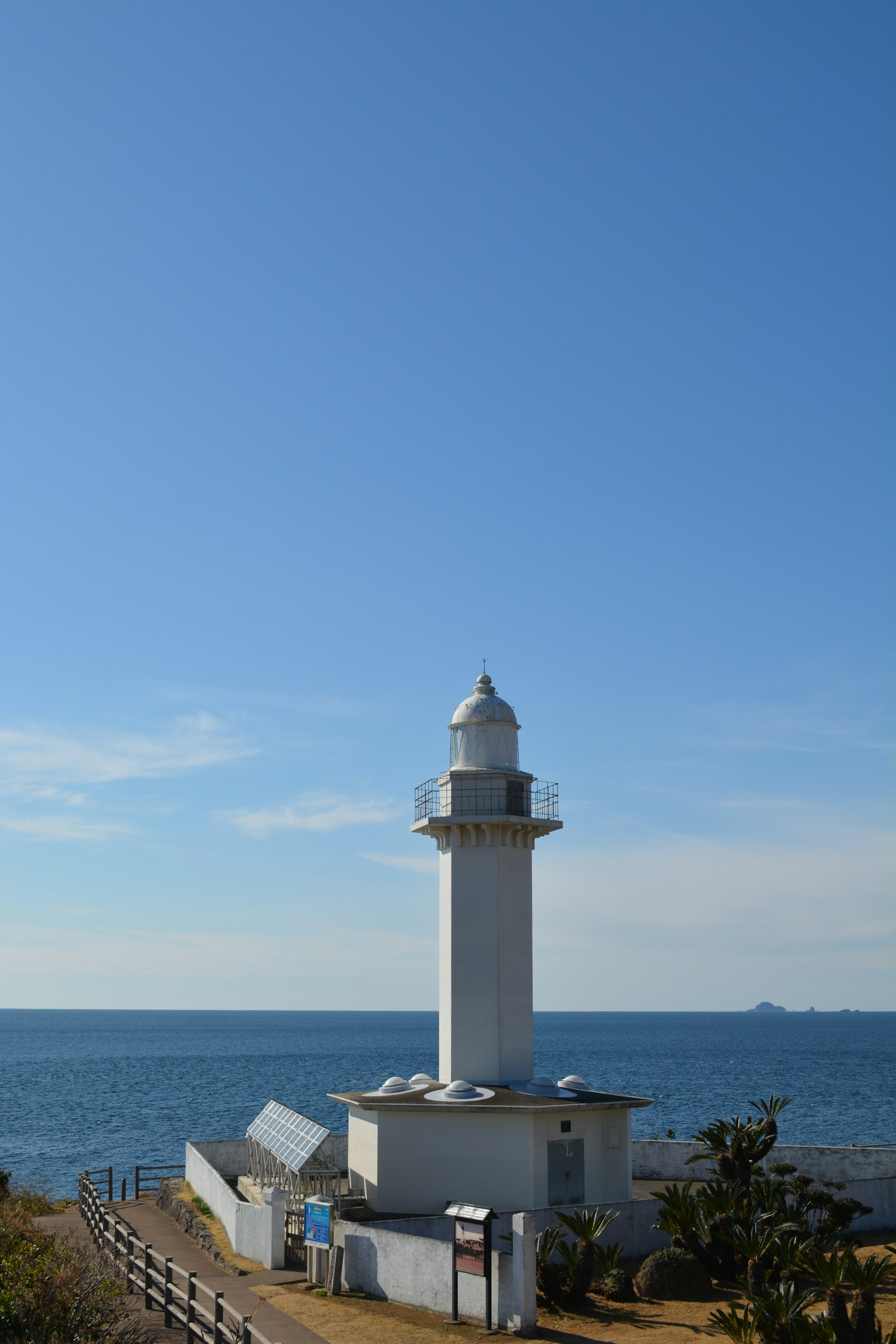 White lighthouse standing against a blue sea and sky