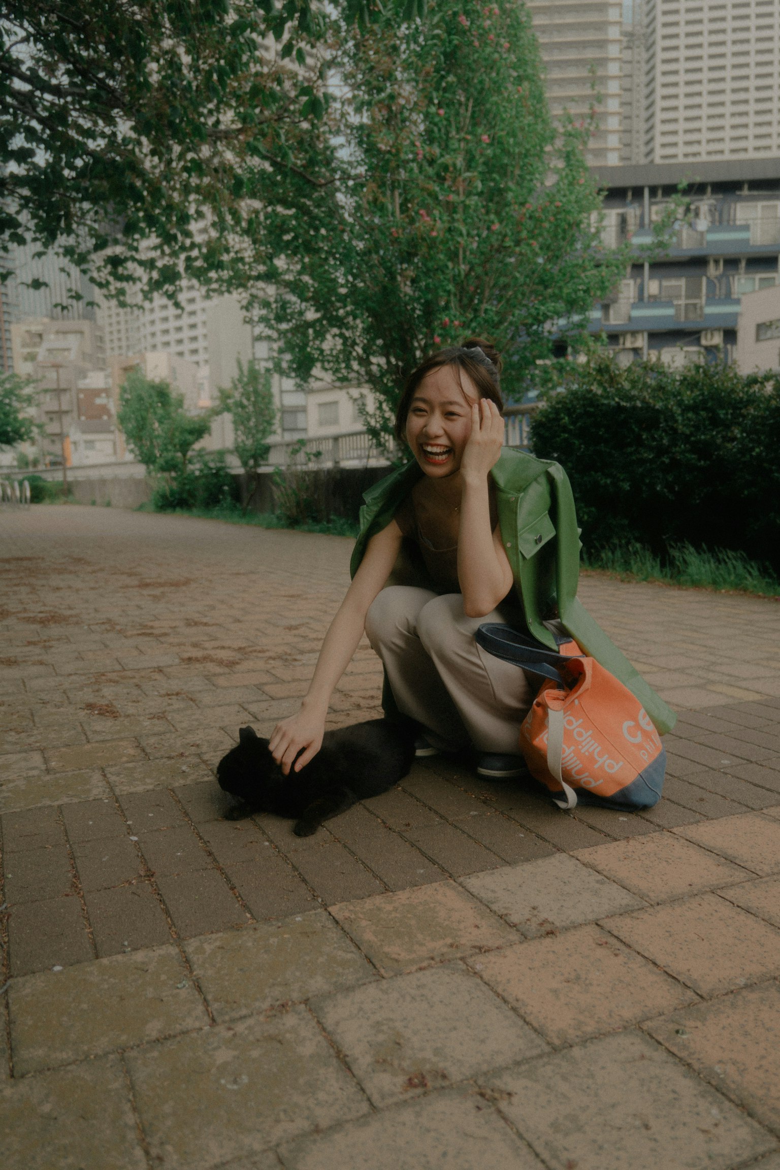 一位微笑的女性在公園裡和一隻黑貓玩耍