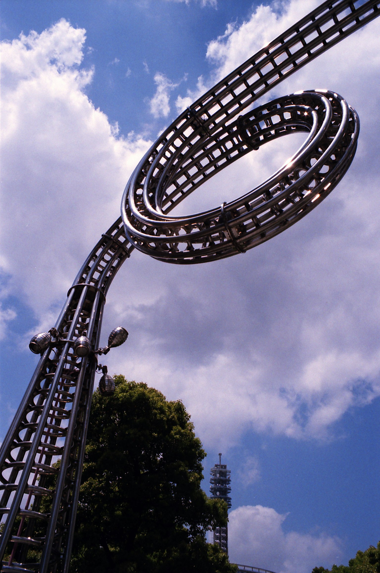 Metallische, schlingenförmige Skulptur, die unter einem blauen Himmel emporragt