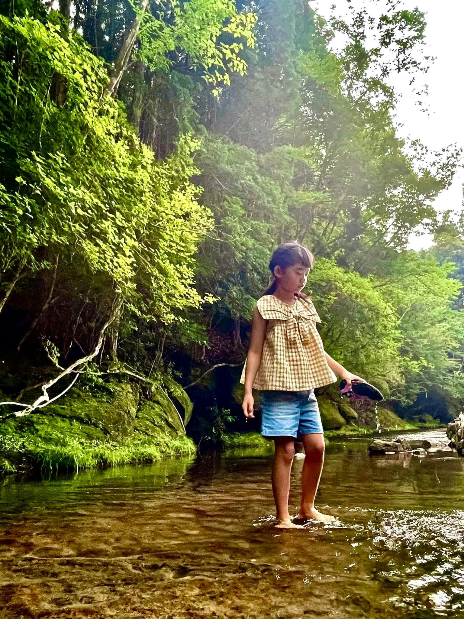 Enfant jouant dans un ruisseau entouré d'une végétation luxuriante
