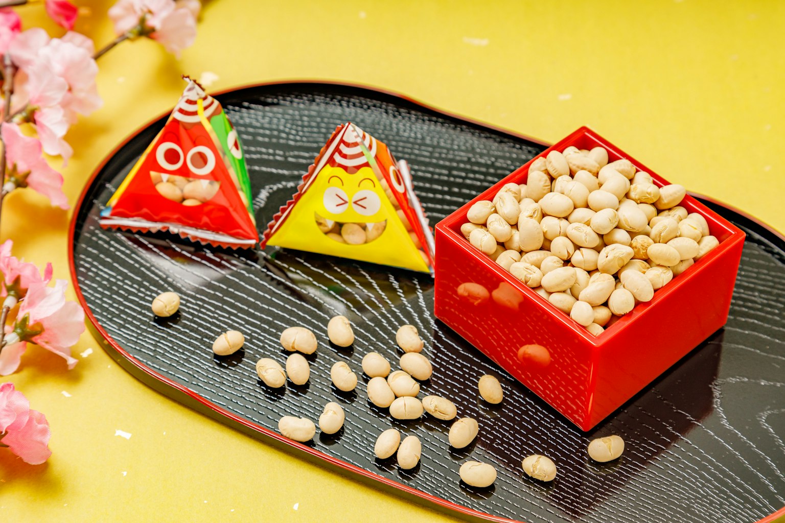 Colorful triangular sweets and a red box filled with beans on a decorative plate