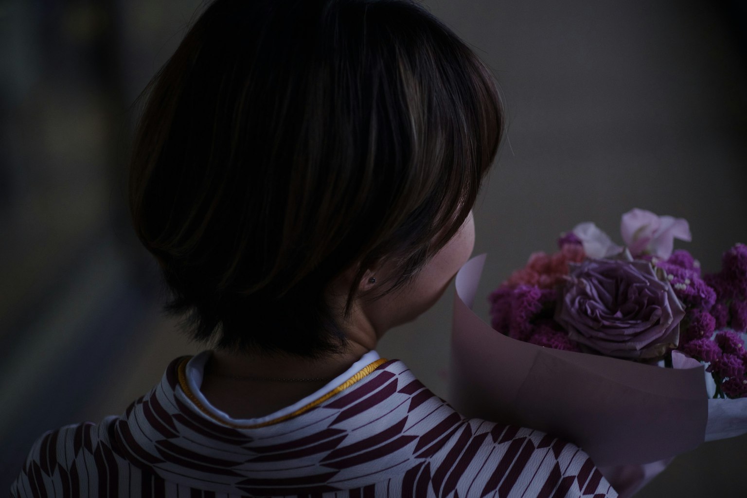 Femme tenant un bouquet de fleurs de dos
