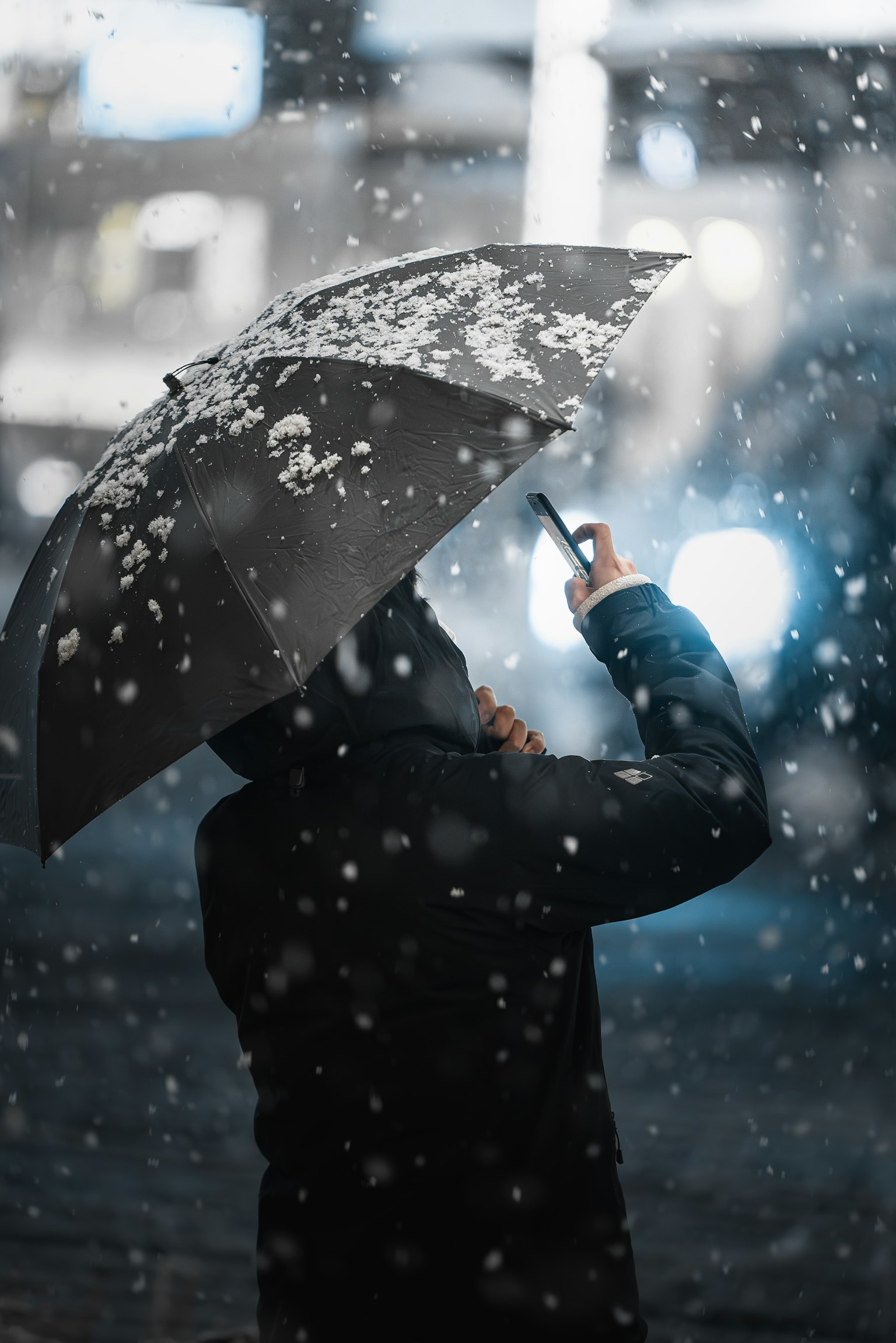 Người cầm ô nhìn lên bầu trời tuyết rơi
