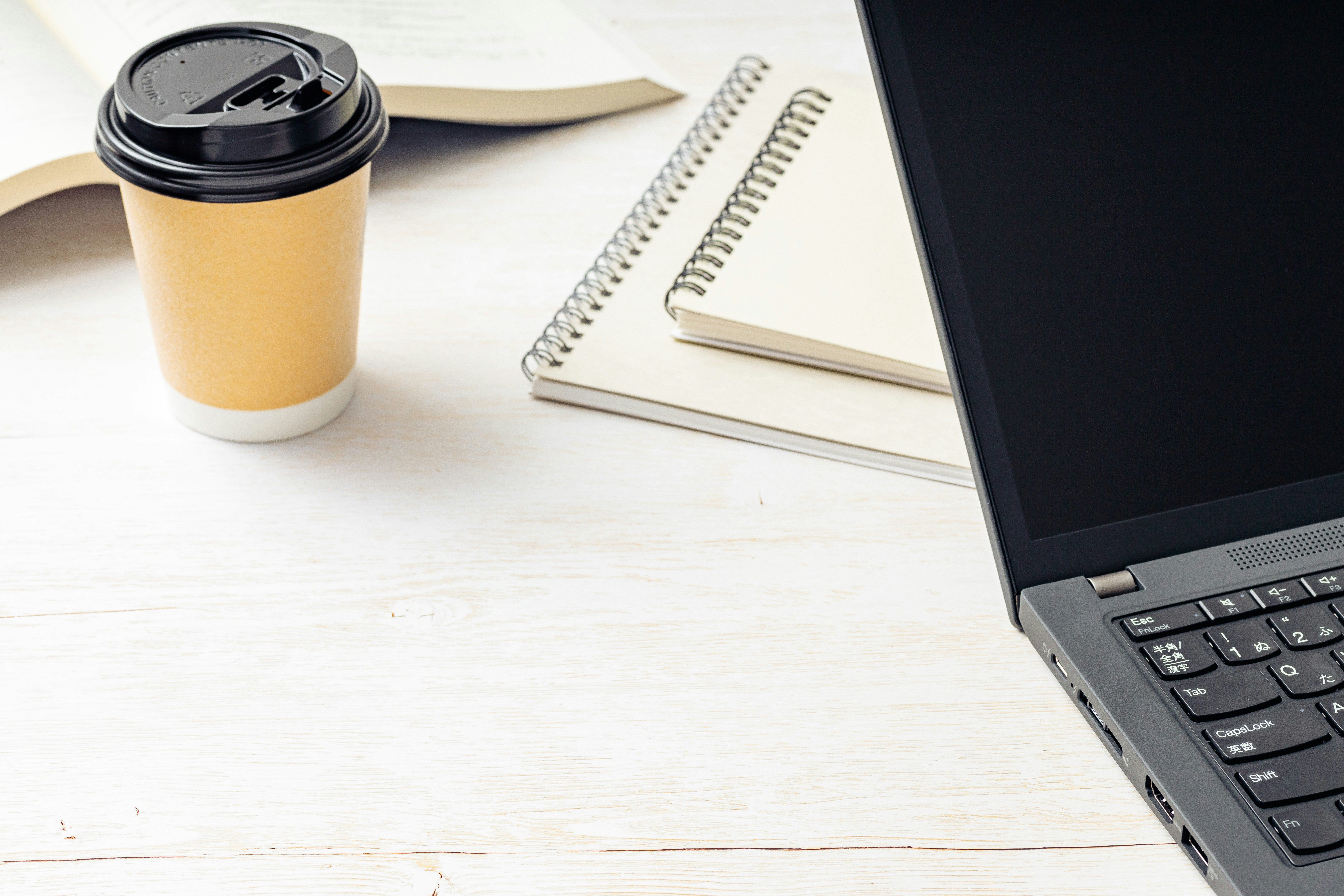 コーヒーとノート、PCが並ぶビジネスデスクの風景