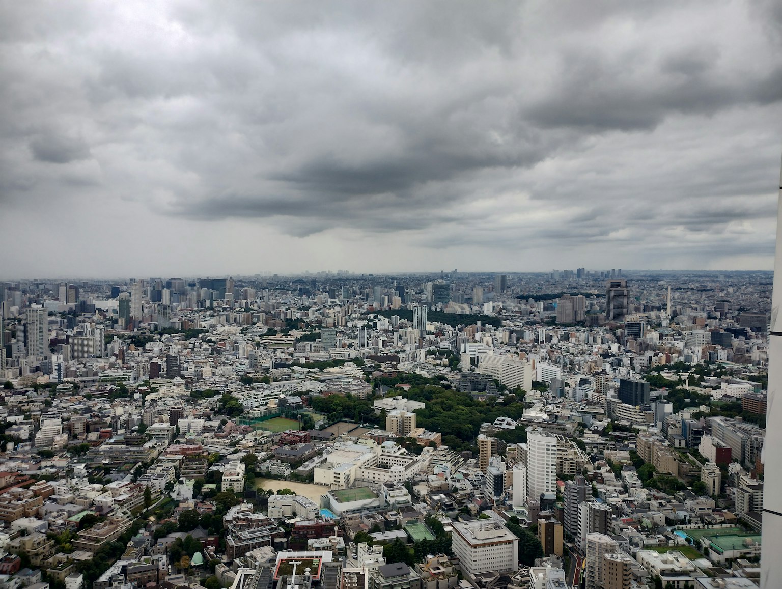 Vista dello skyline di Tokyo con grattacieli e parchi sotto un cielo nuvoloso