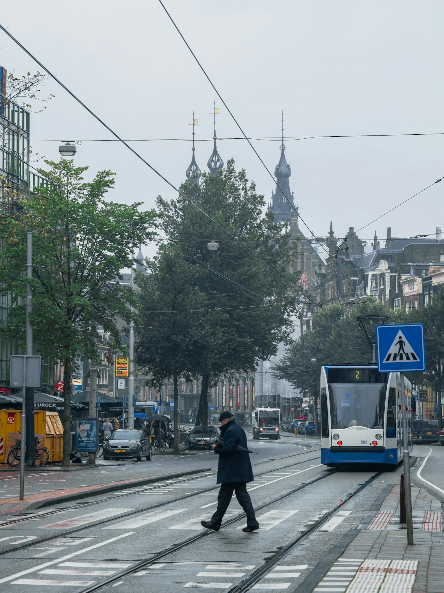 Ein Mann, der durch eine neblige Straße mit einer Straßenbahn im Hintergrund geht