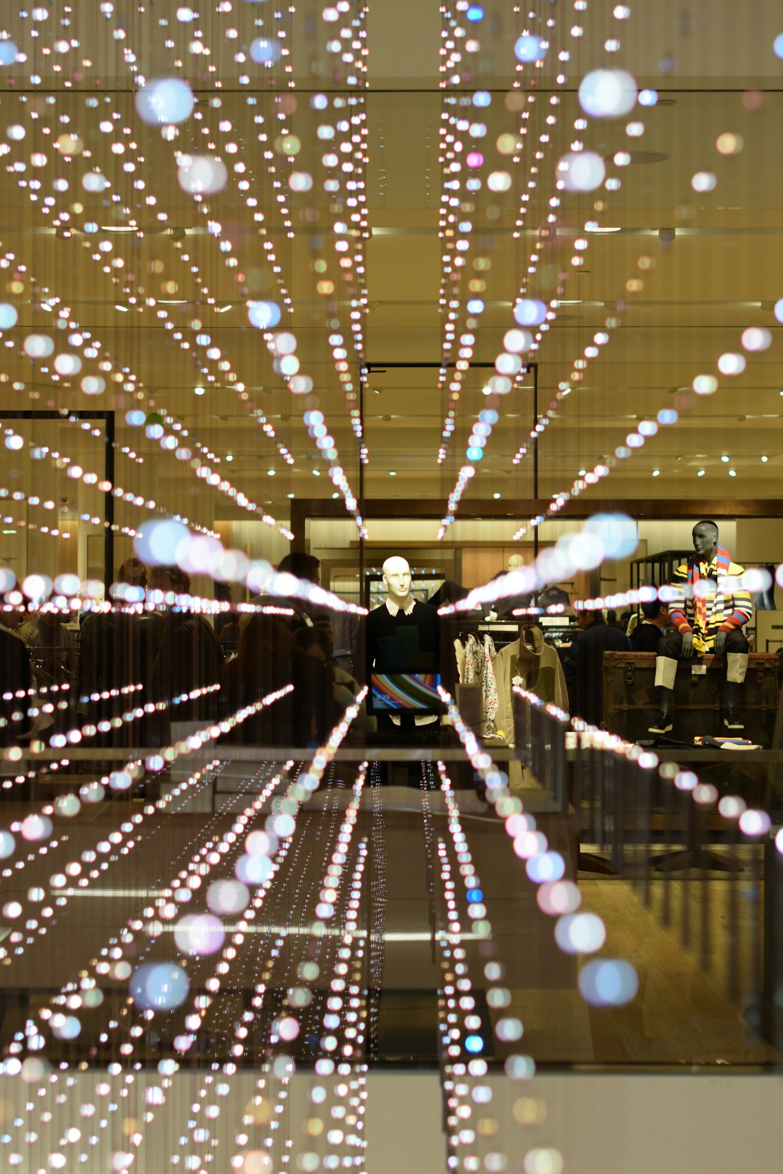 A mannequin standing in a shop window surrounded by glowing light dots
