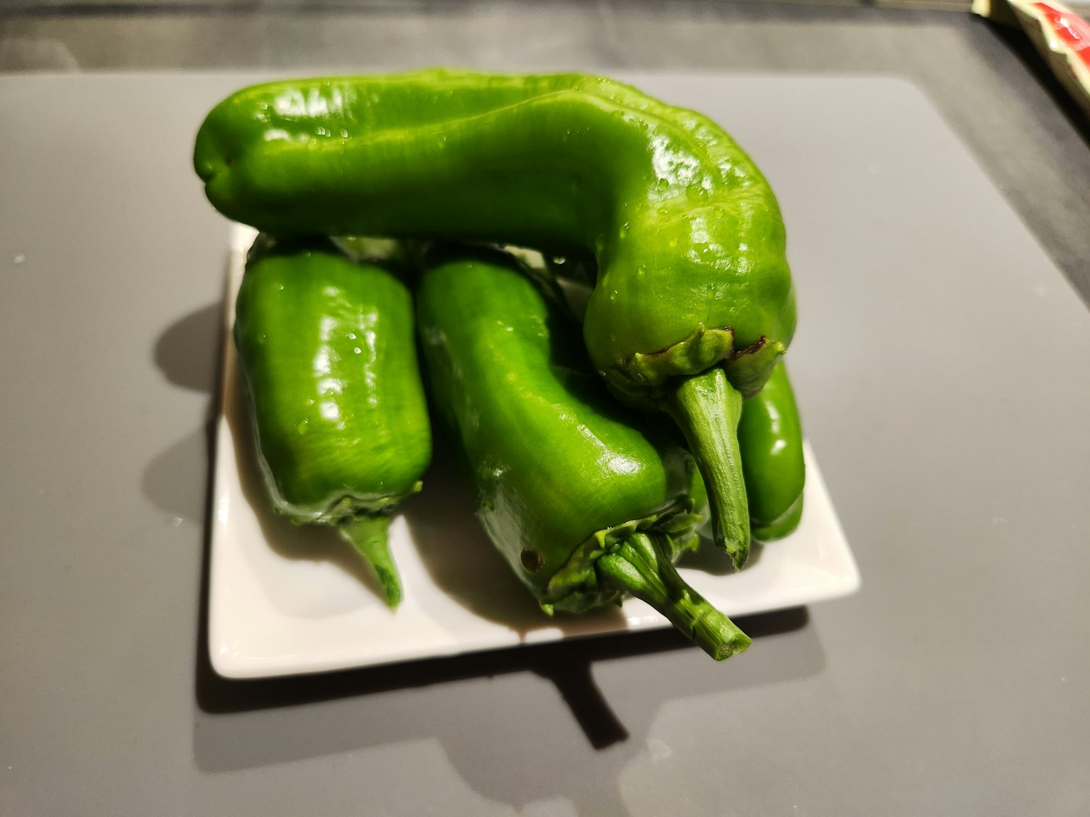 Grüne Chilischoten auf einem kleinen weißen Teller angeordnet