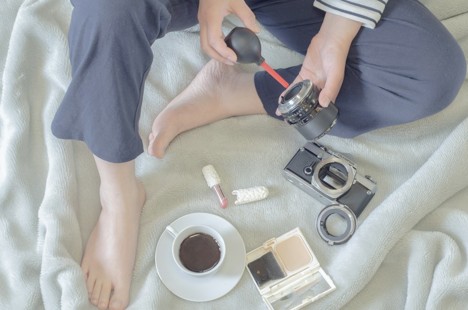 Persona che pulisce una macchina fotografica con caffè e cosmetici su una coperta