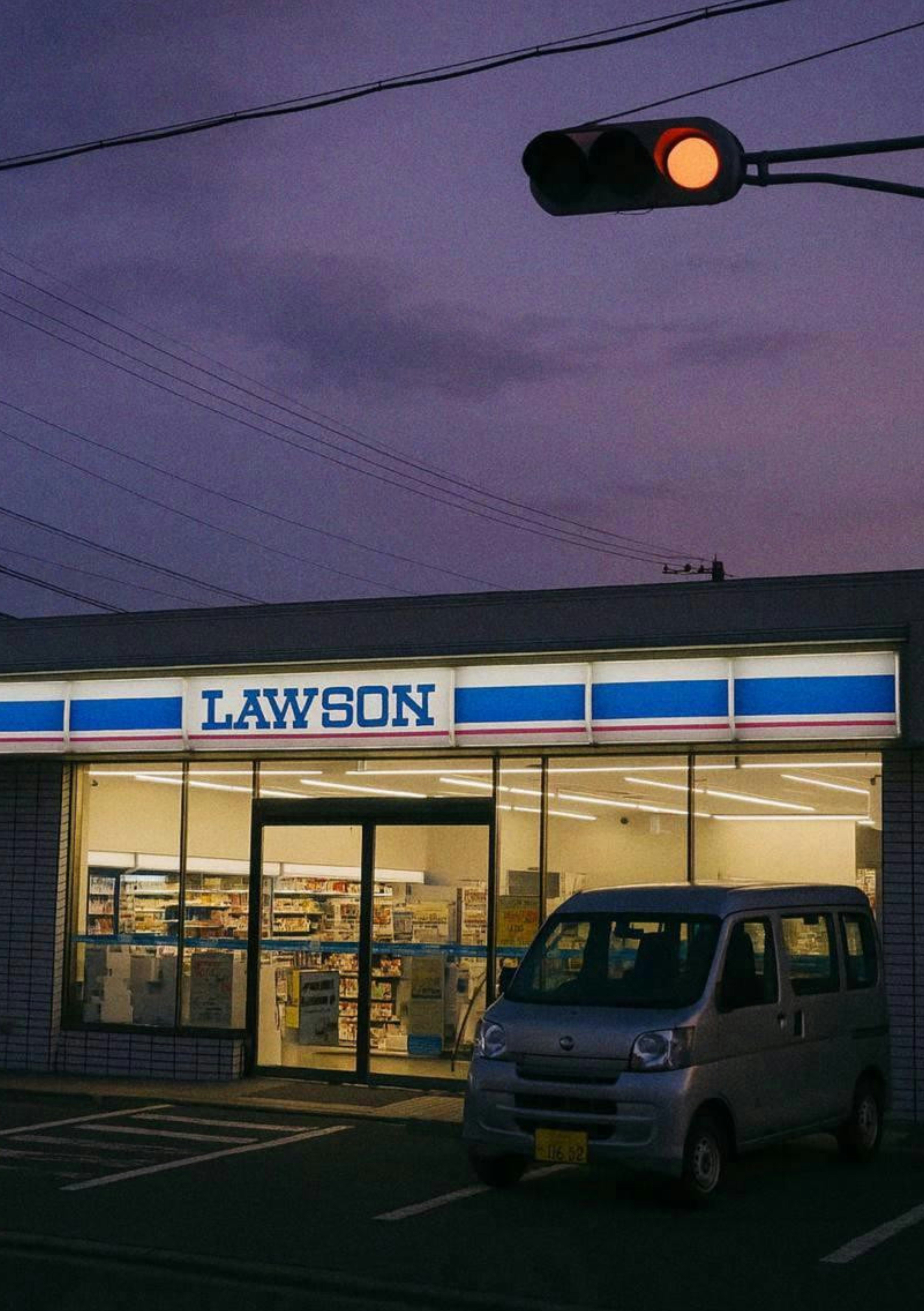 夕暮れのLAWSON店舗前の駐車スペースと車