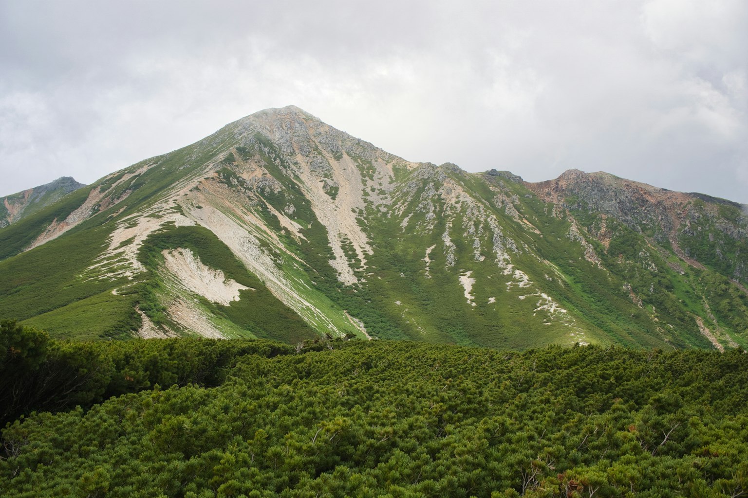 Paisaje montañoso verde con cielo nublado