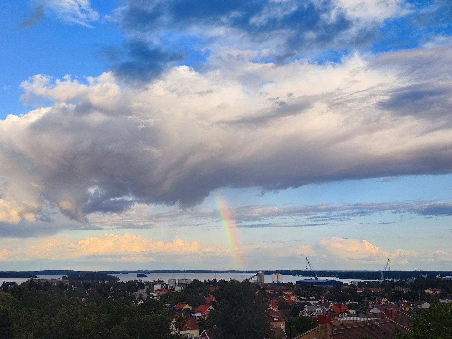 Una vista panoramica di un arcobaleno sopra un cielo blu e nuvole sopra una città
