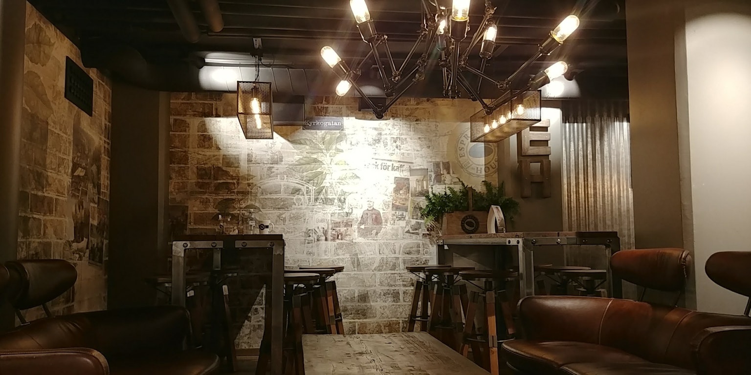 Interno di un caffè con illuminazione calda tavoli in legno e sedie in pelle che creano un'atmosfera semplice e accogliente
