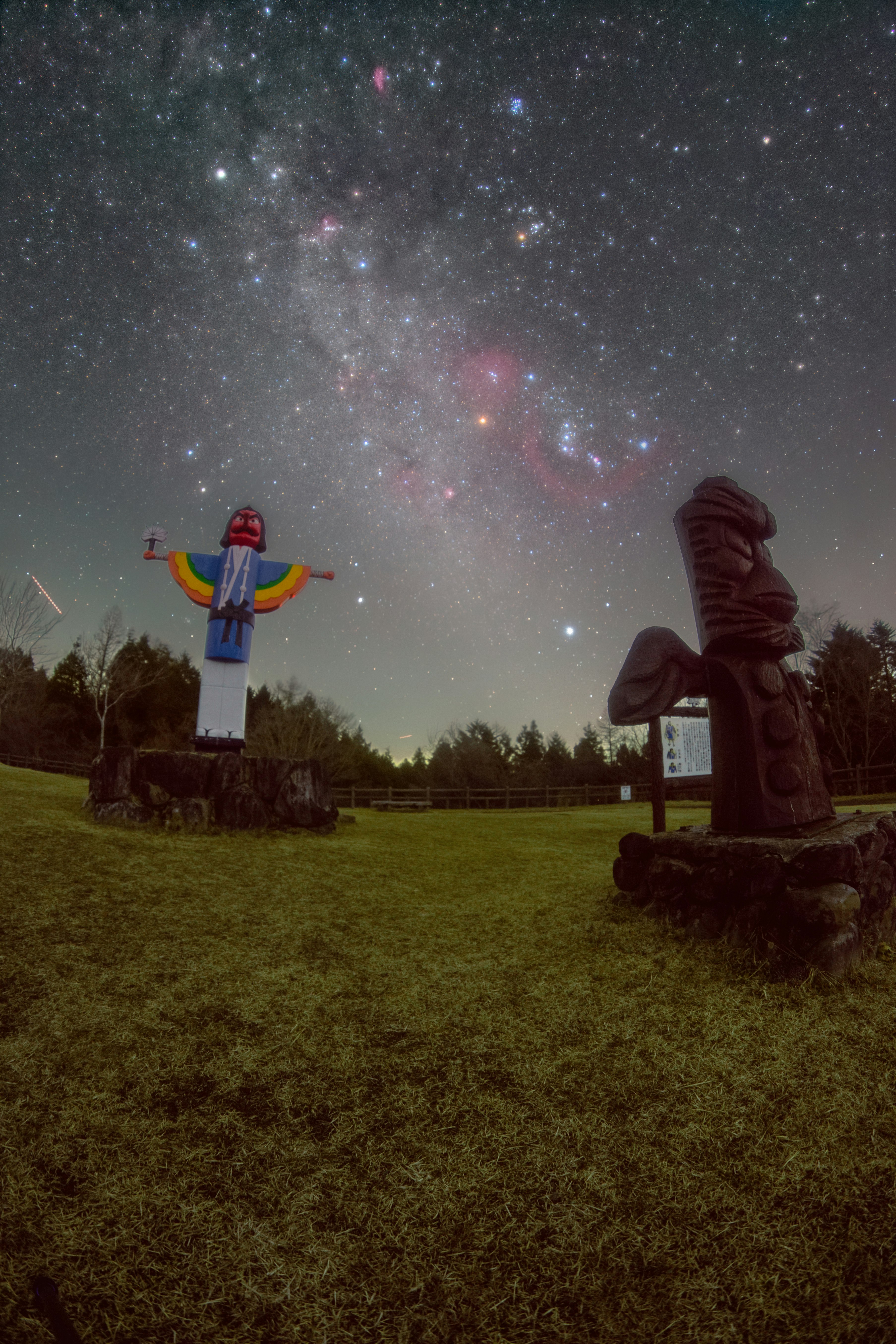 星空の下に立つカラフルな像と古代の彫刻がある風景
