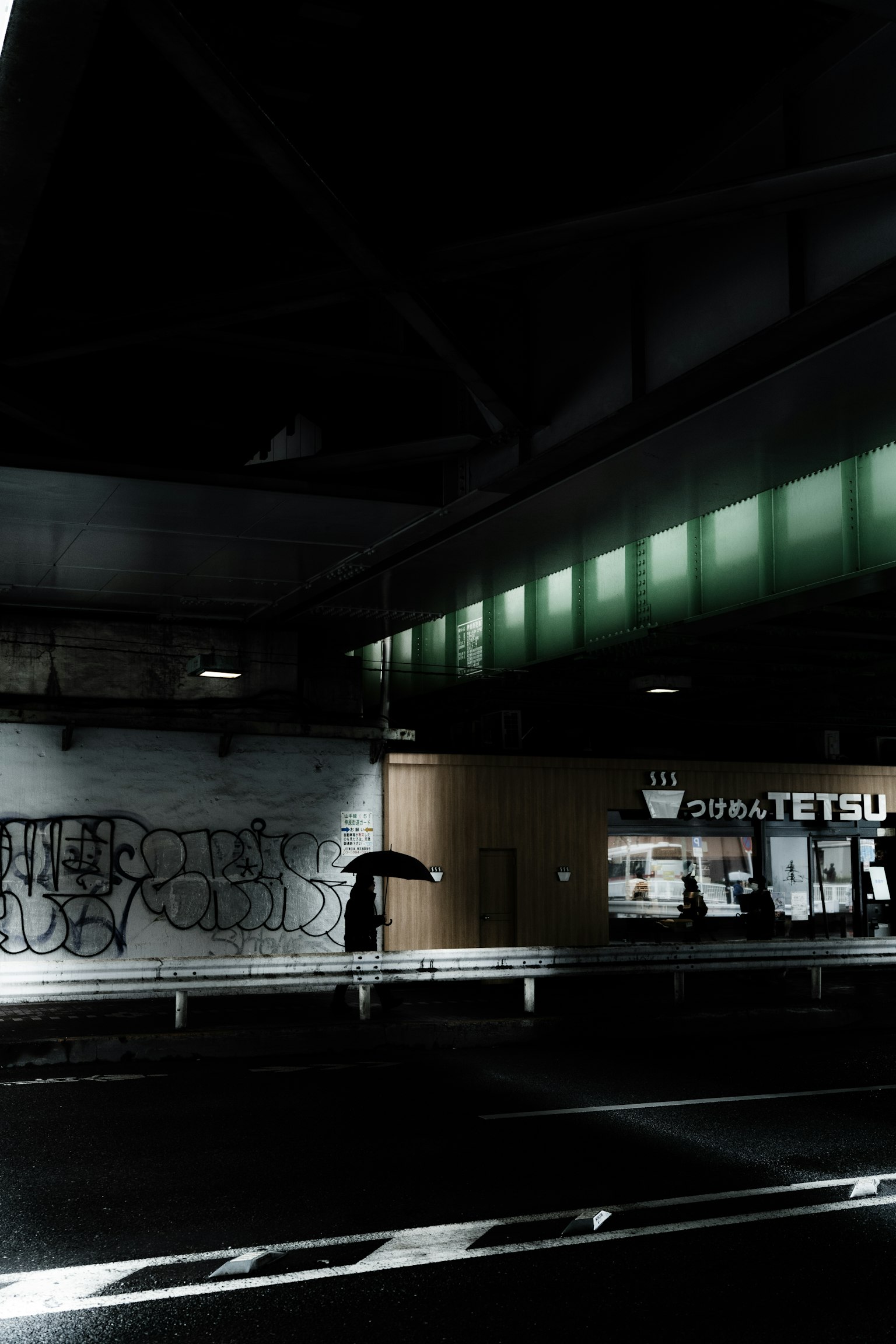 Scena urbana buia con un binario della stazione illuminato da luci verdi e graffiti