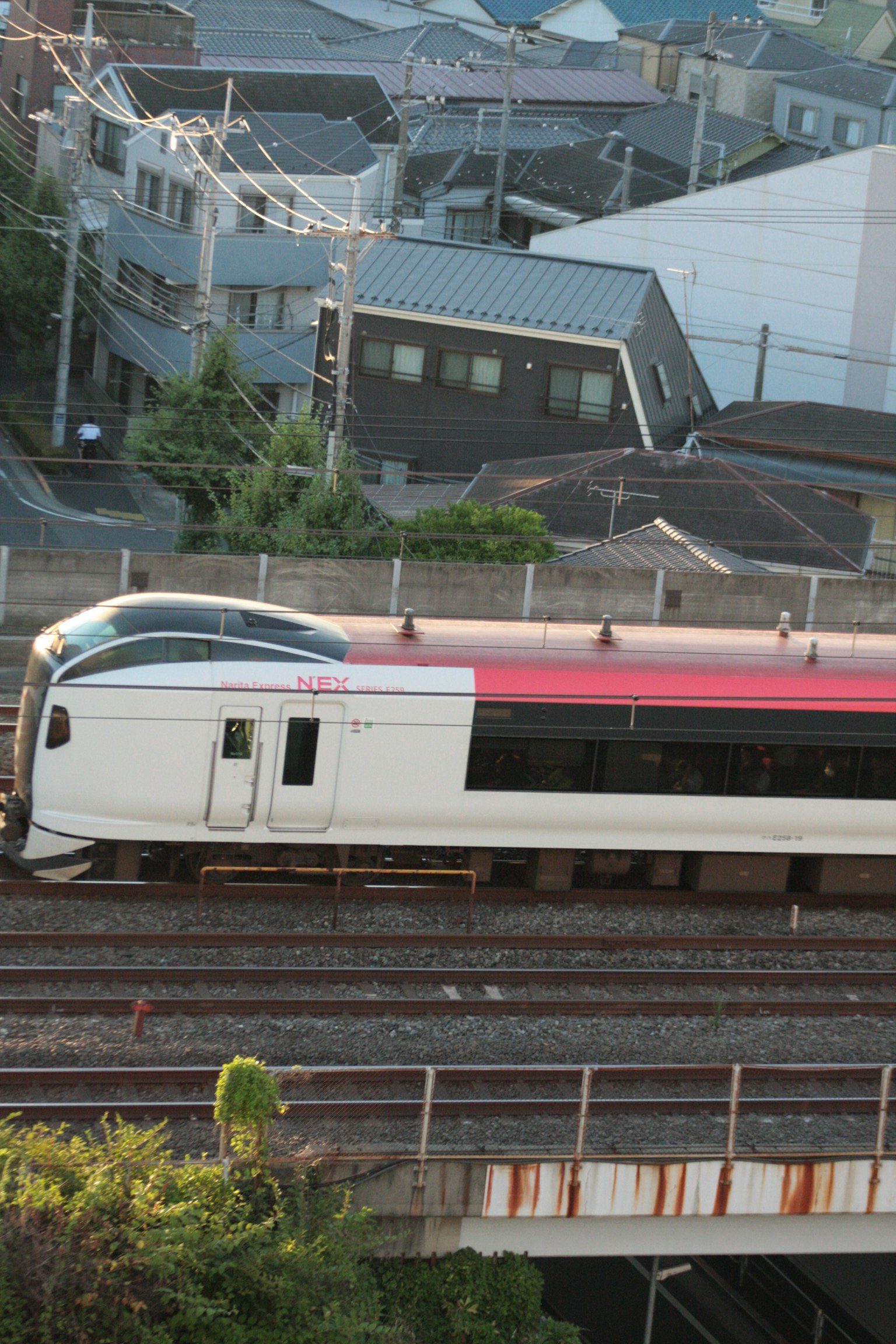 Train Shinkansen passant sur des rails avec des bâtiments résidentiels en arrière-plan