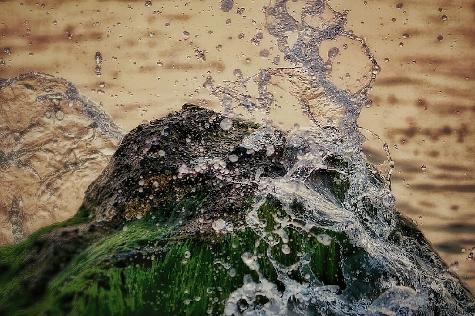水從覆蓋著綠色苔蘚的岩石上濺起的場景