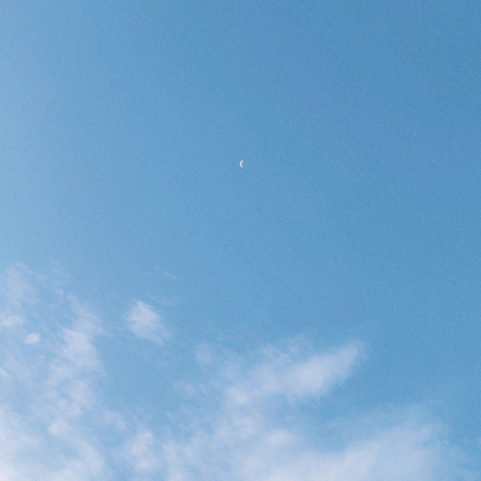 晴朗的藍天上有一小月亮和柔軟的雲
