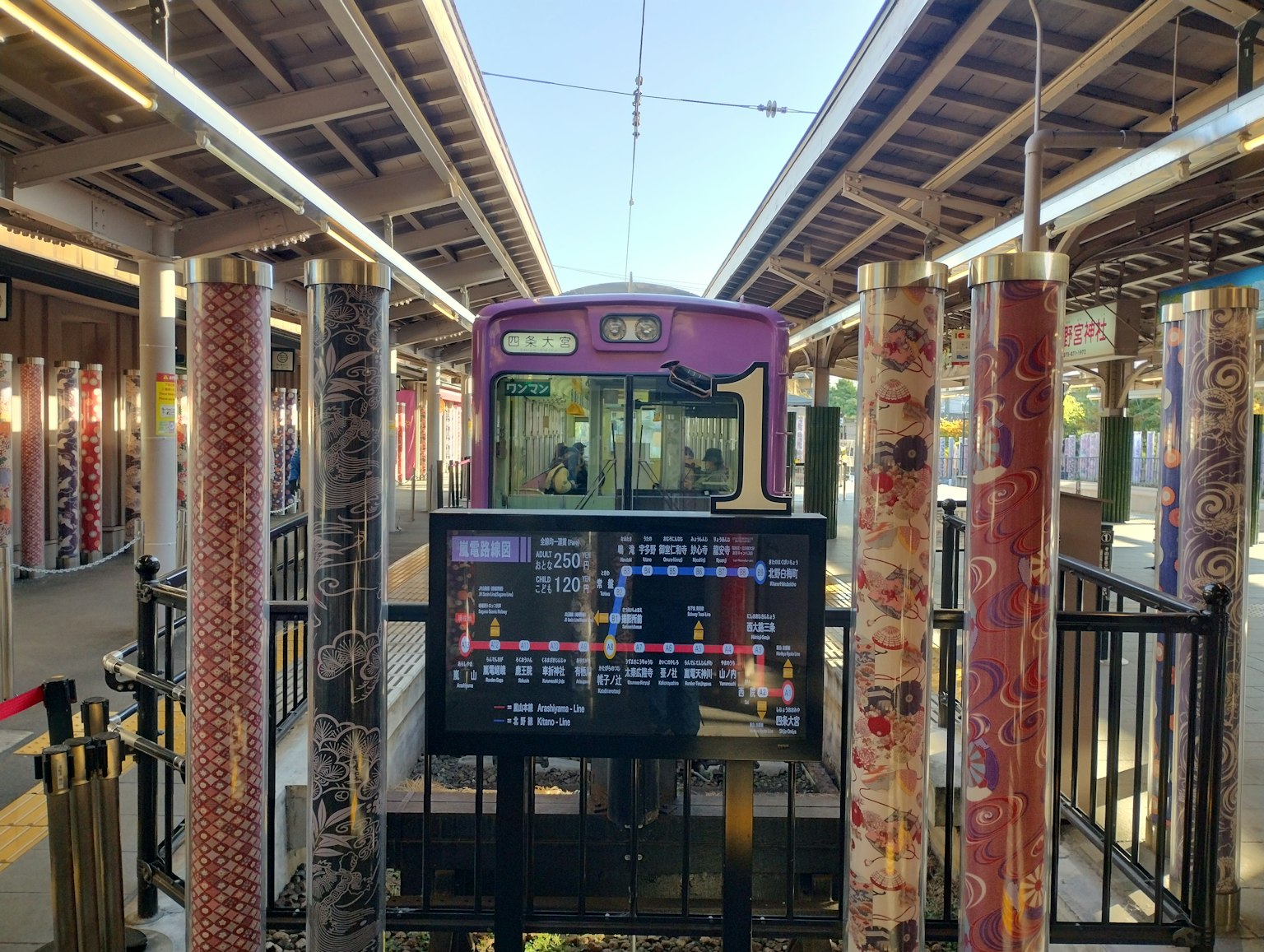 色彩繽紛的柱子環繞著一個車站，紫色火車停靠