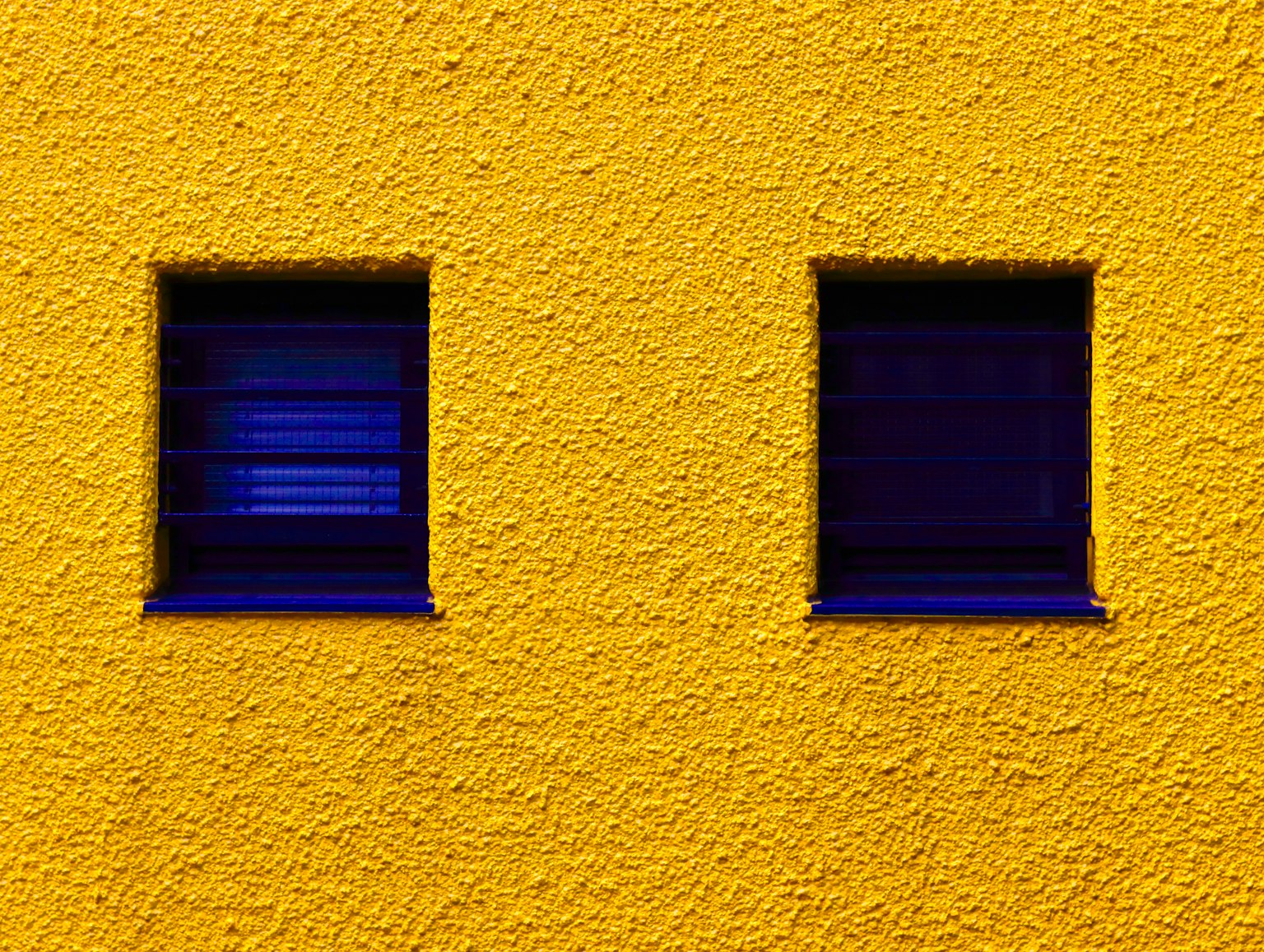 Diseño simple con dos ventanas azules en una pared amarilla