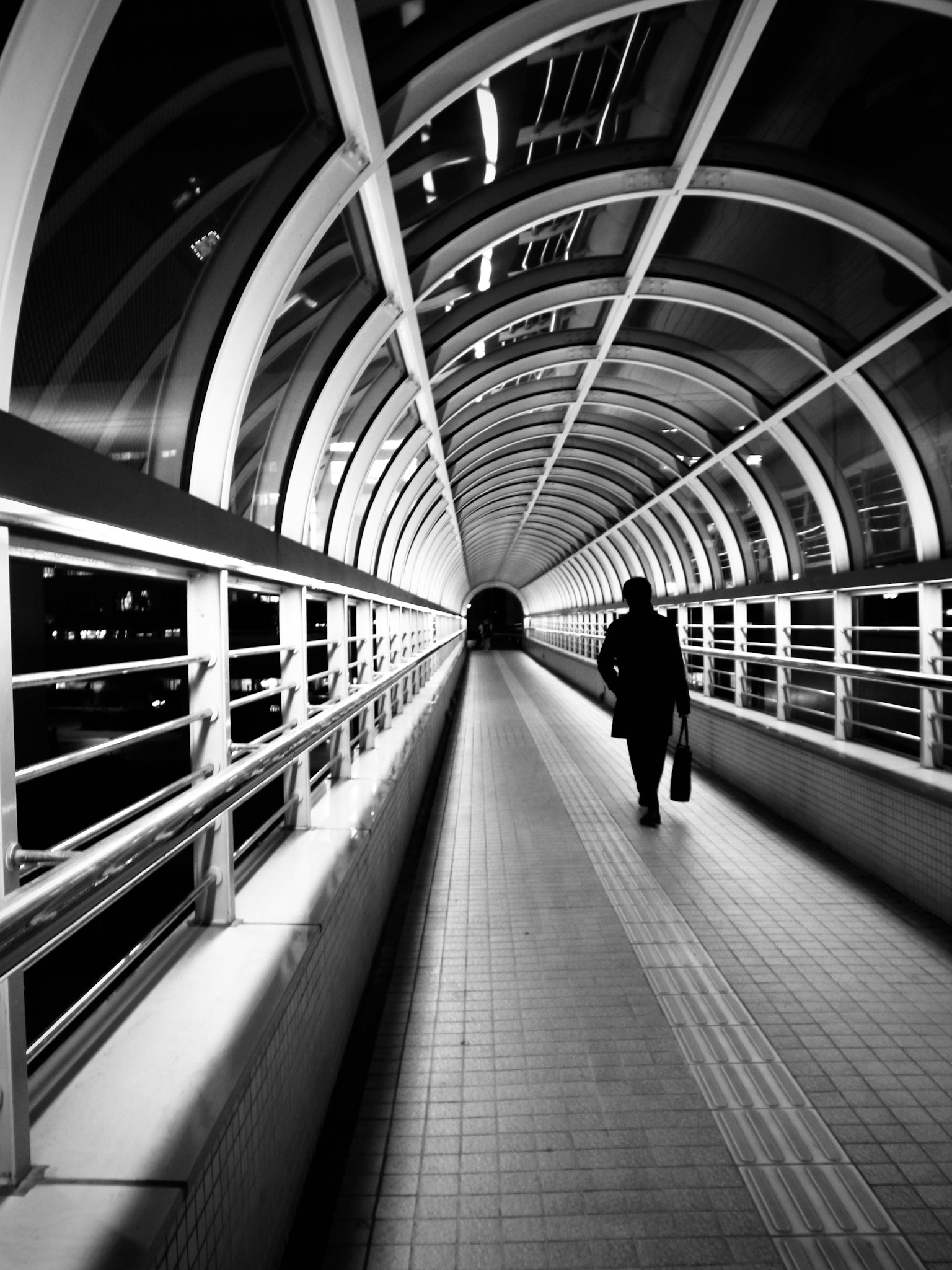 Silhouette d'une personne marchant dans un tunnel en noir et blanc