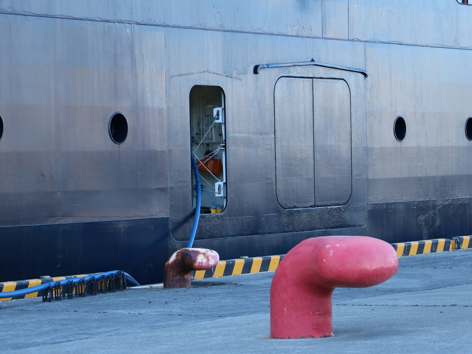 Una scena portuale con un'apertura sul lato di una nave e un bollard rosso prominente