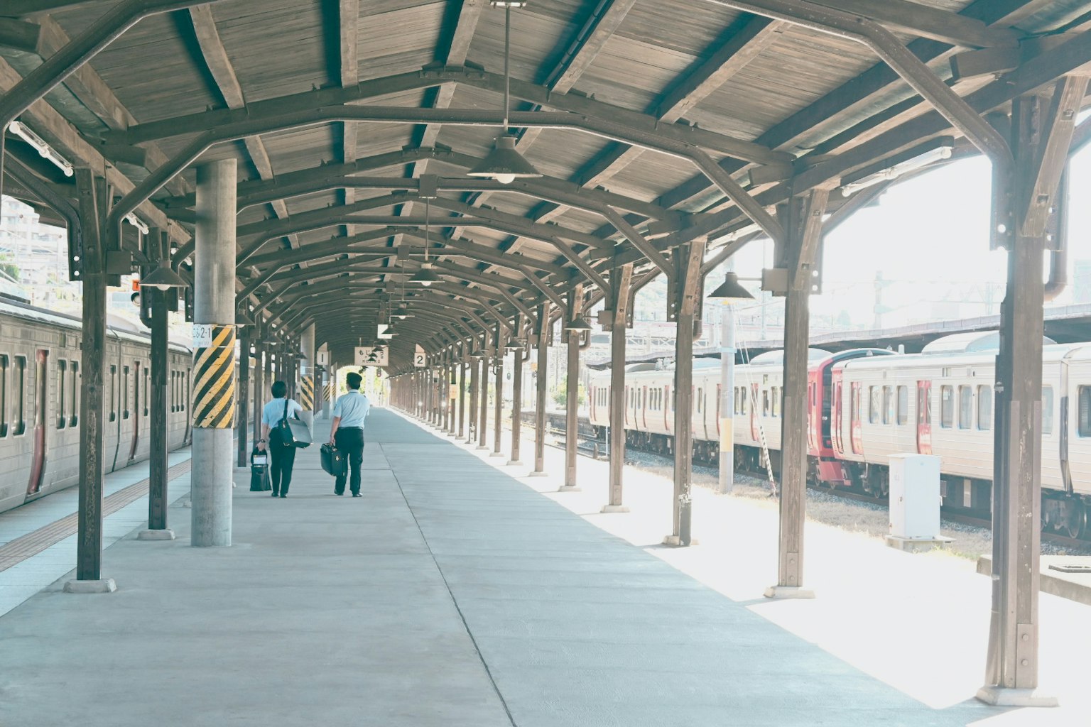 Due persone che camminano su una banchina della stazione con treni vicini