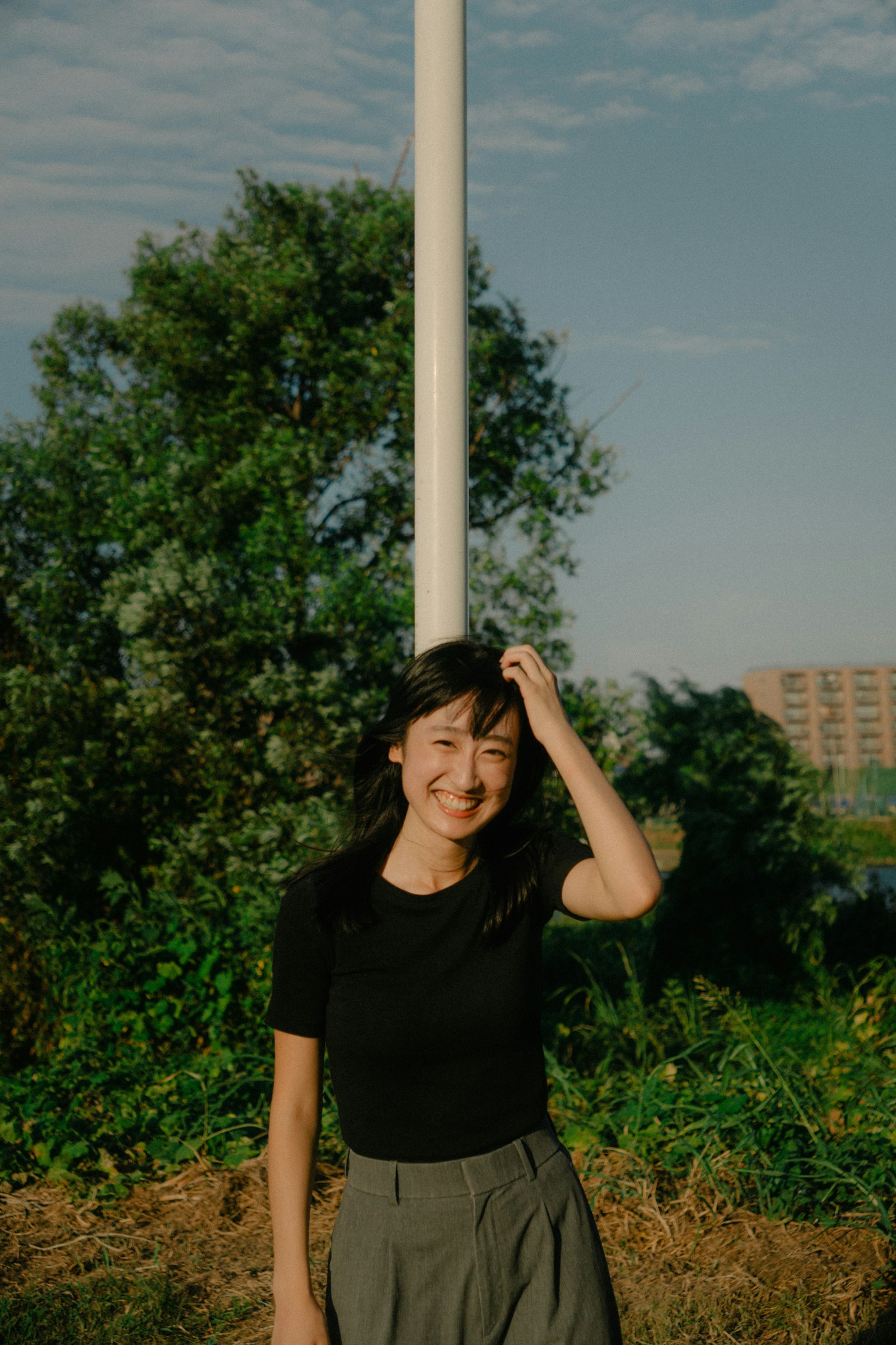 Une femme souriante debout dans un parc avec de la verdure en arrière-plan
