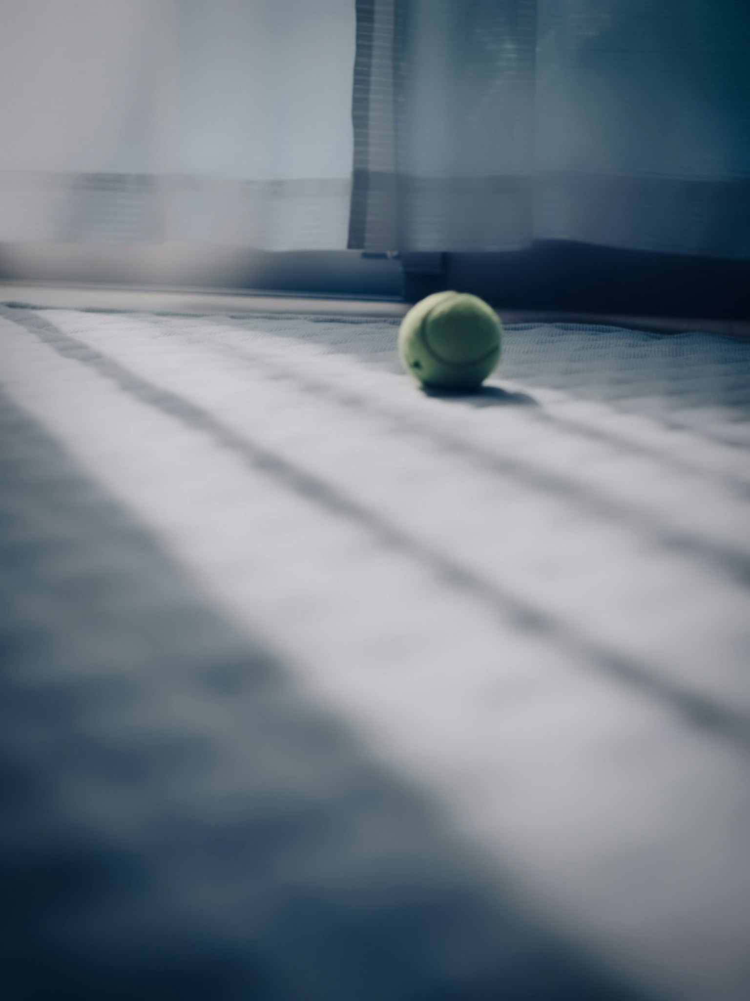 Una pallina da tennis che riposa sul pavimento con ombre morbide