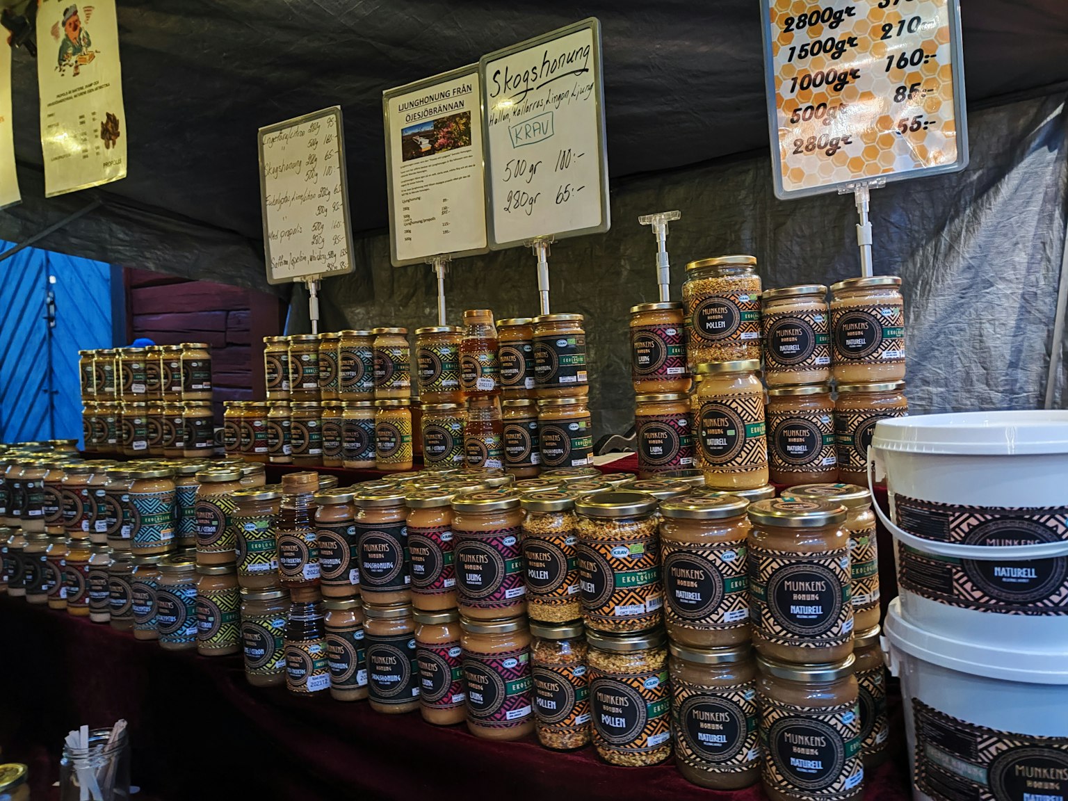 Interior de un puesto de mercado con tarros de mermeladas y encurtidos