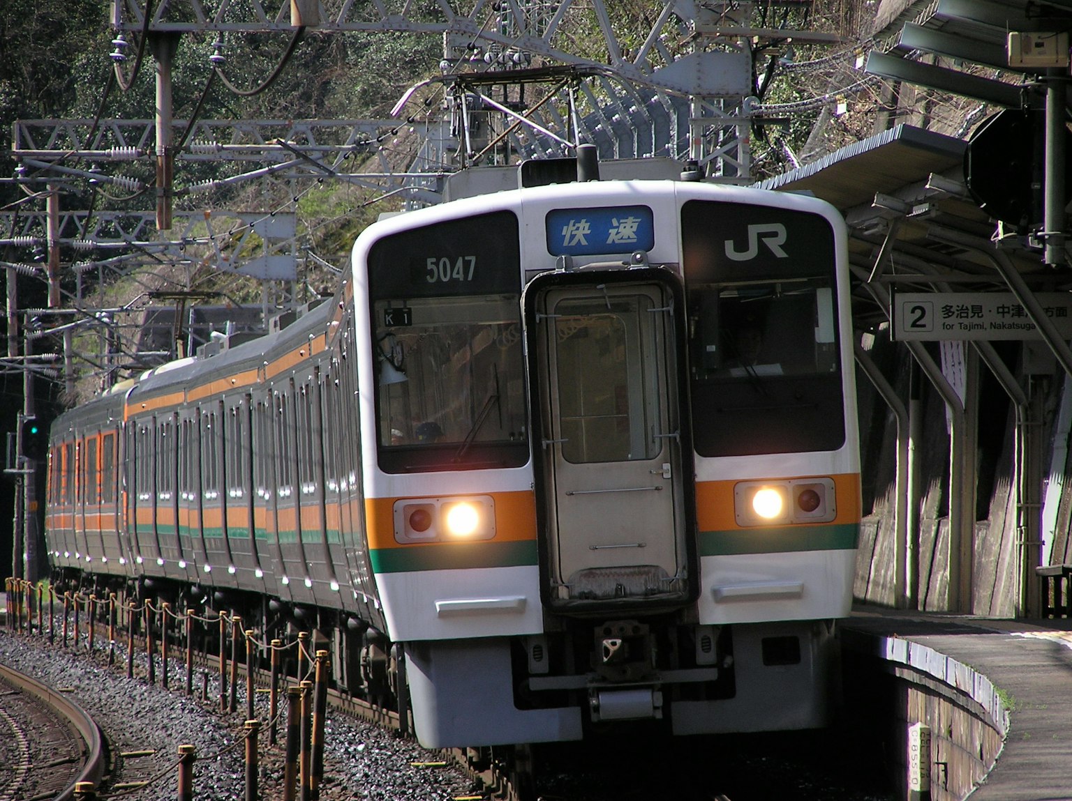 Train JR tournant dans un virage avec une station en arrière-plan