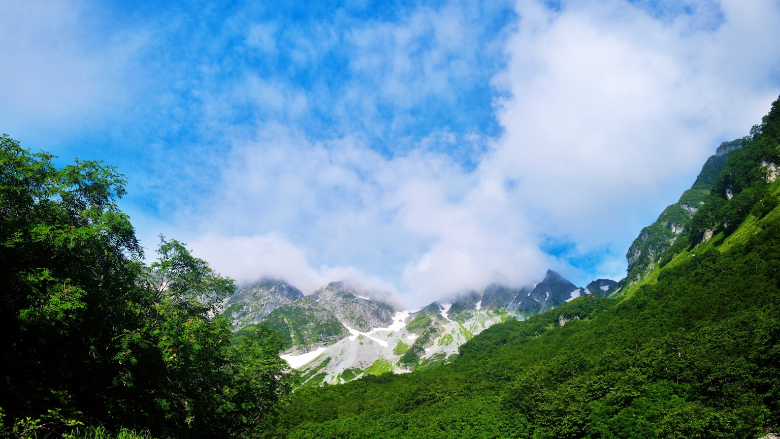 Montagnes verdoyantes sous un ciel bleu avec des nuages blancs