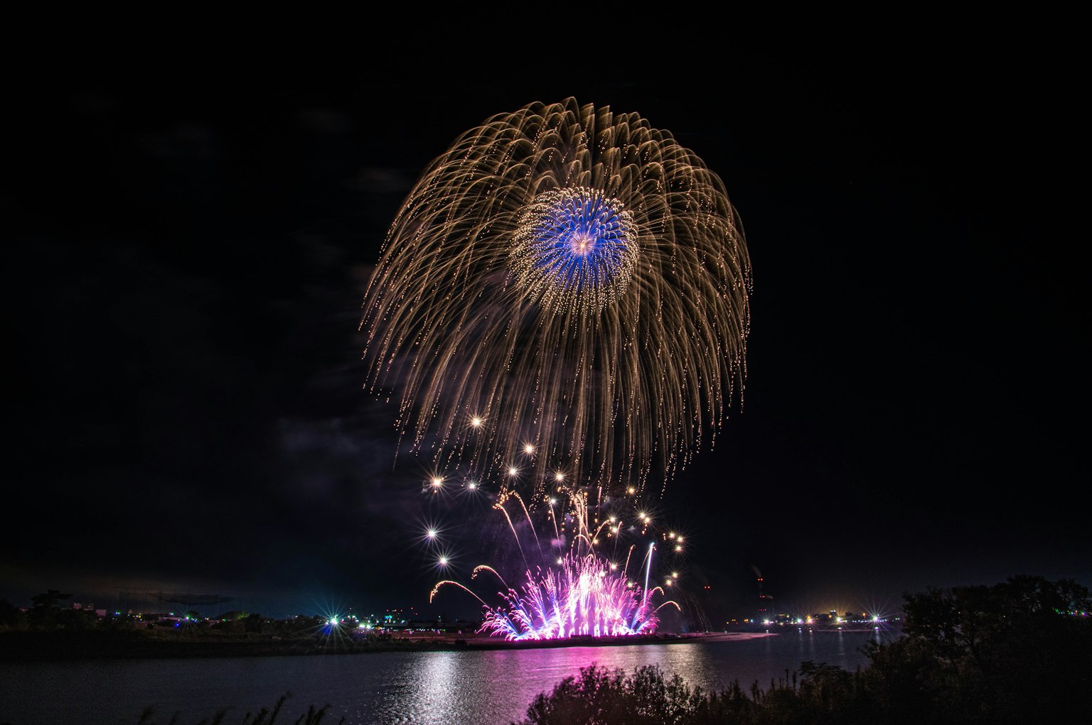 Vibrant fireworks bursting in the night sky over water
