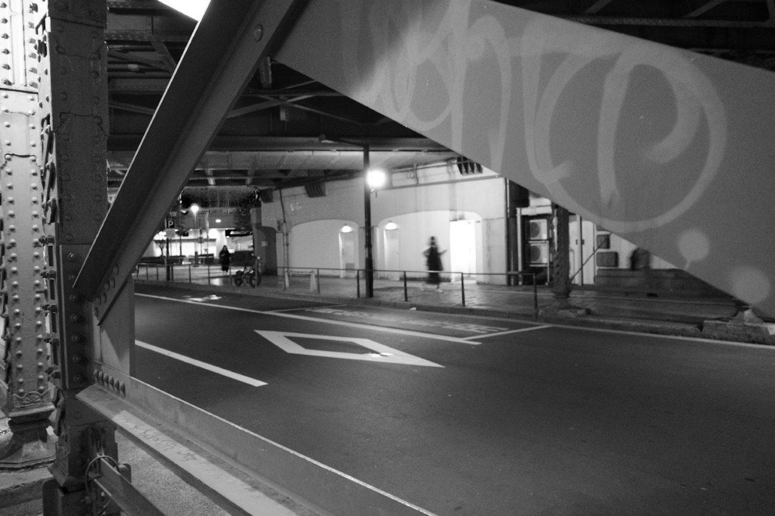 Scena urbana in bianco e nero con struttura di ponte e lampione