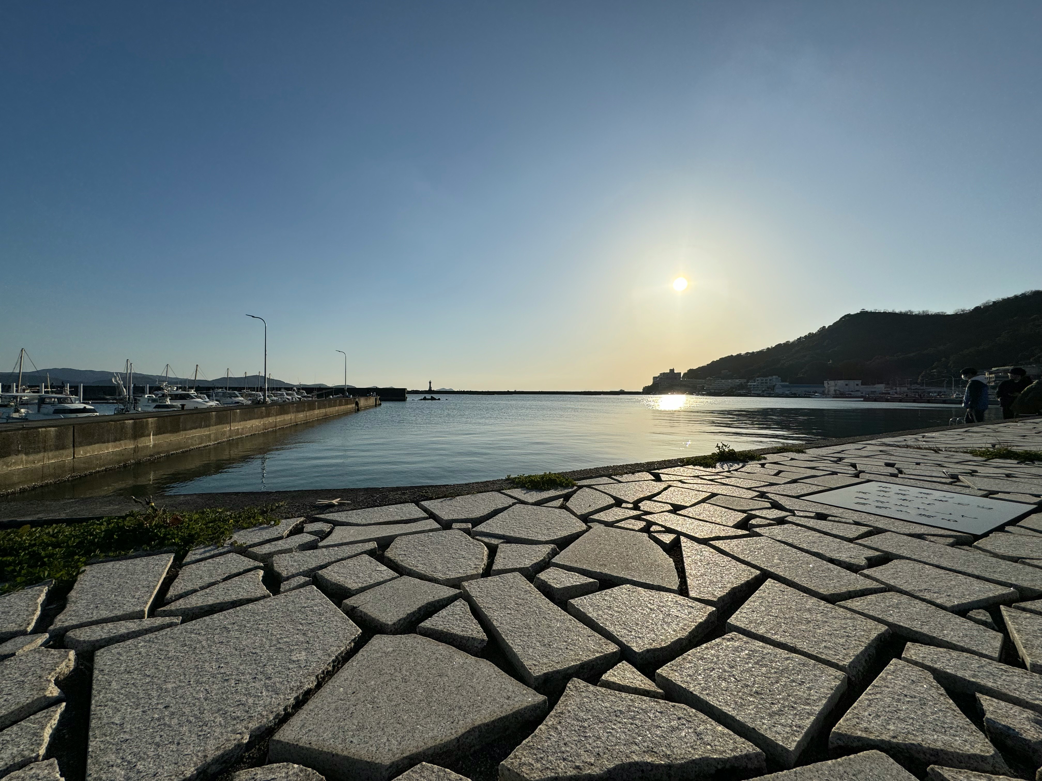 和歌山県和歌浦の漁港の防波堤と海面、夕日が差す画像