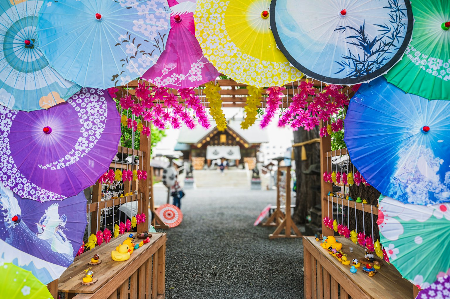 Bunte Regenschirme, die einen Eingang mit Blumen und Dekorationen schmücken