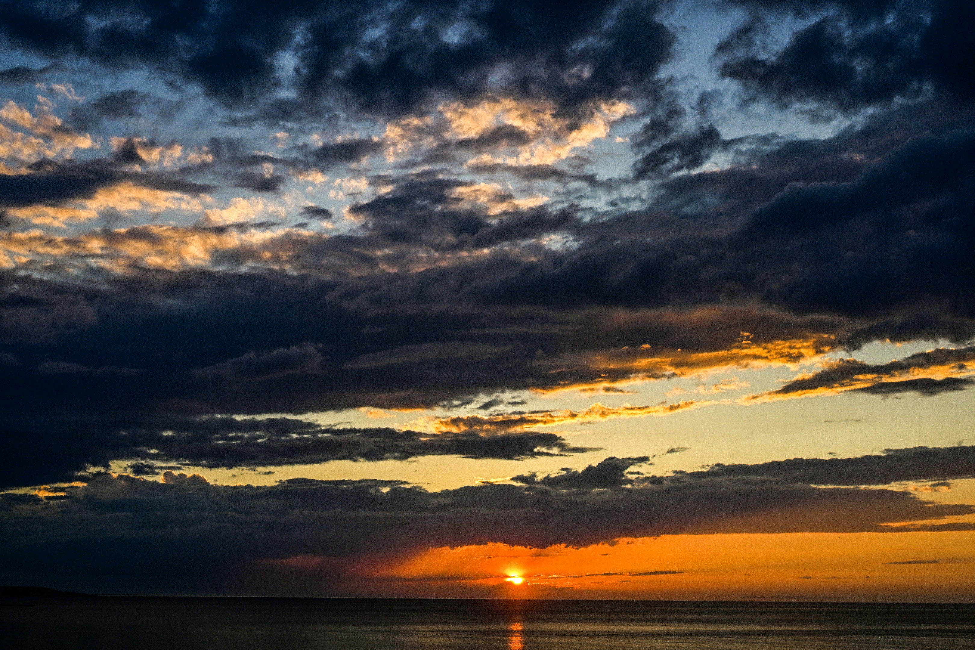 夕焼けの海面に広がる雲と光のグラデーション