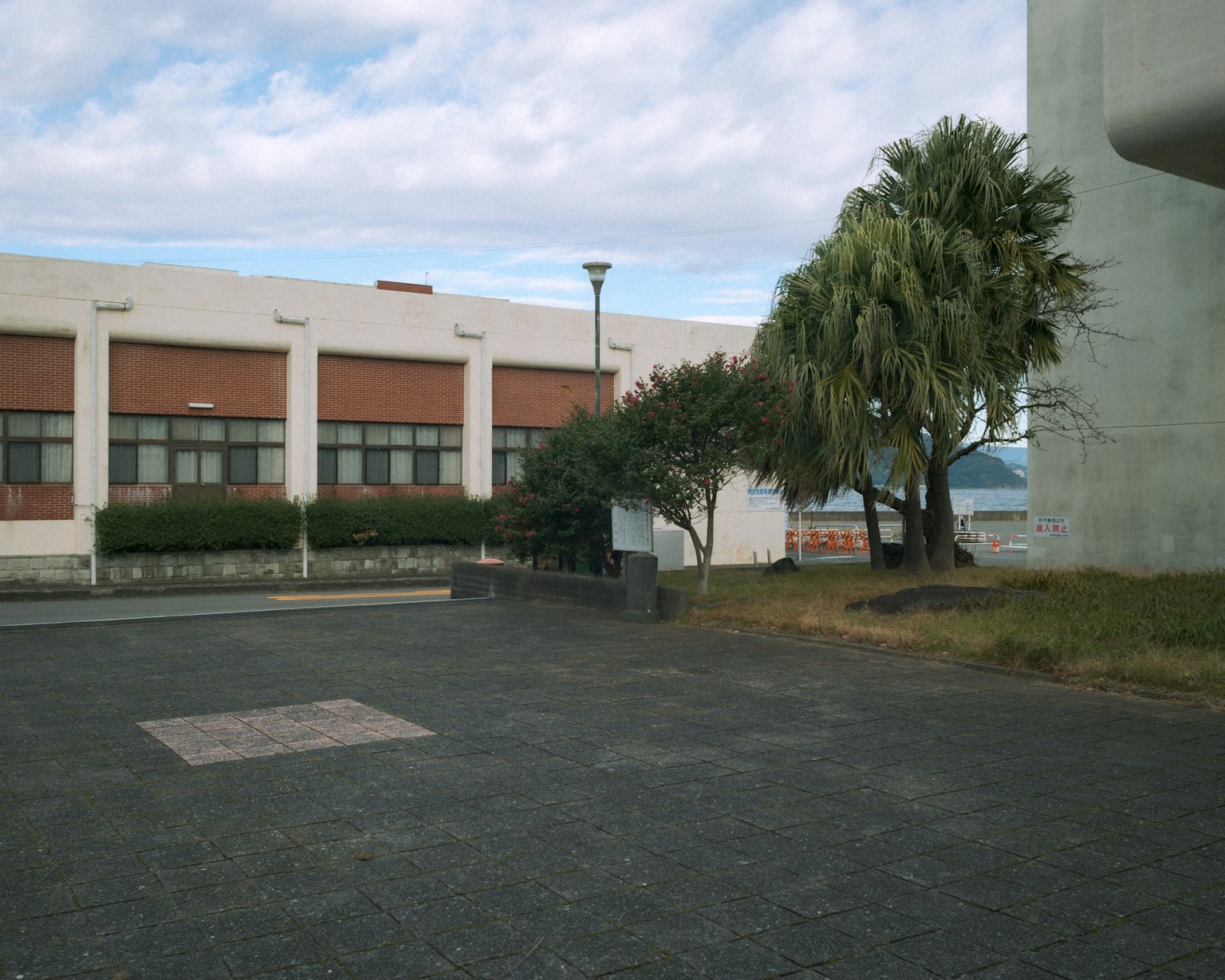 景觀中有一棟白色建築和綠色樹木 在部分多雲的天空下