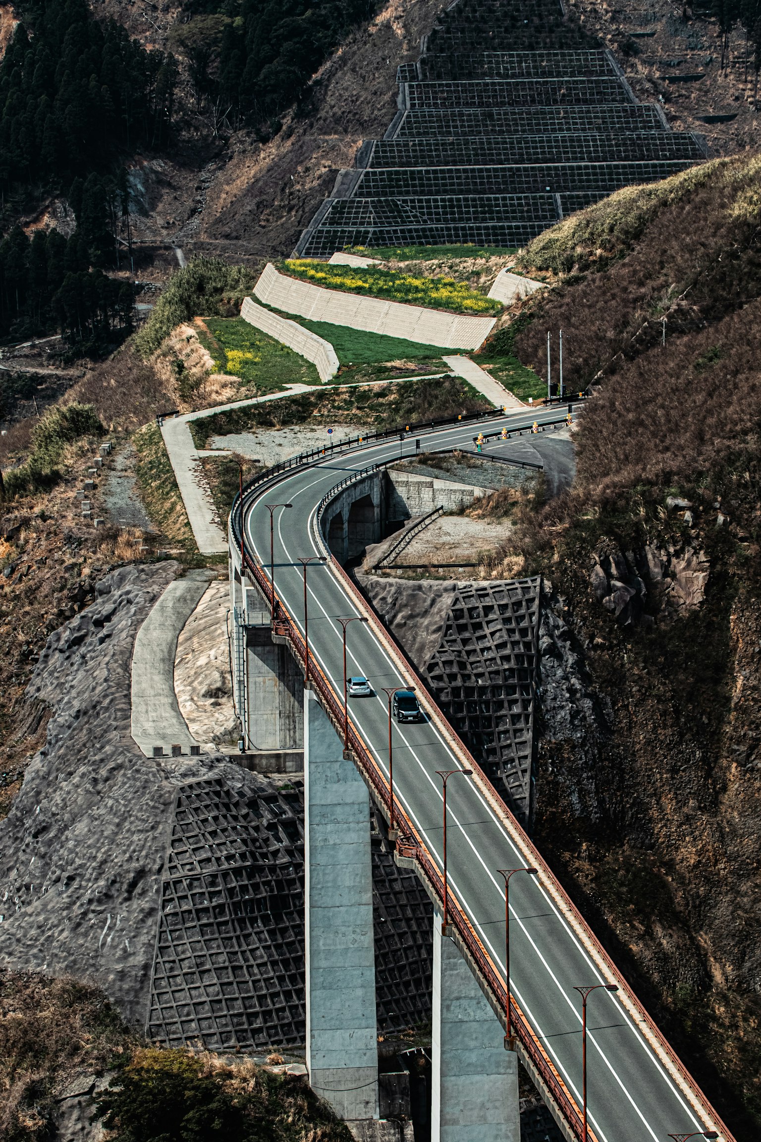 Un ponte moderno e una strada tortuosa lungo un pendio montano