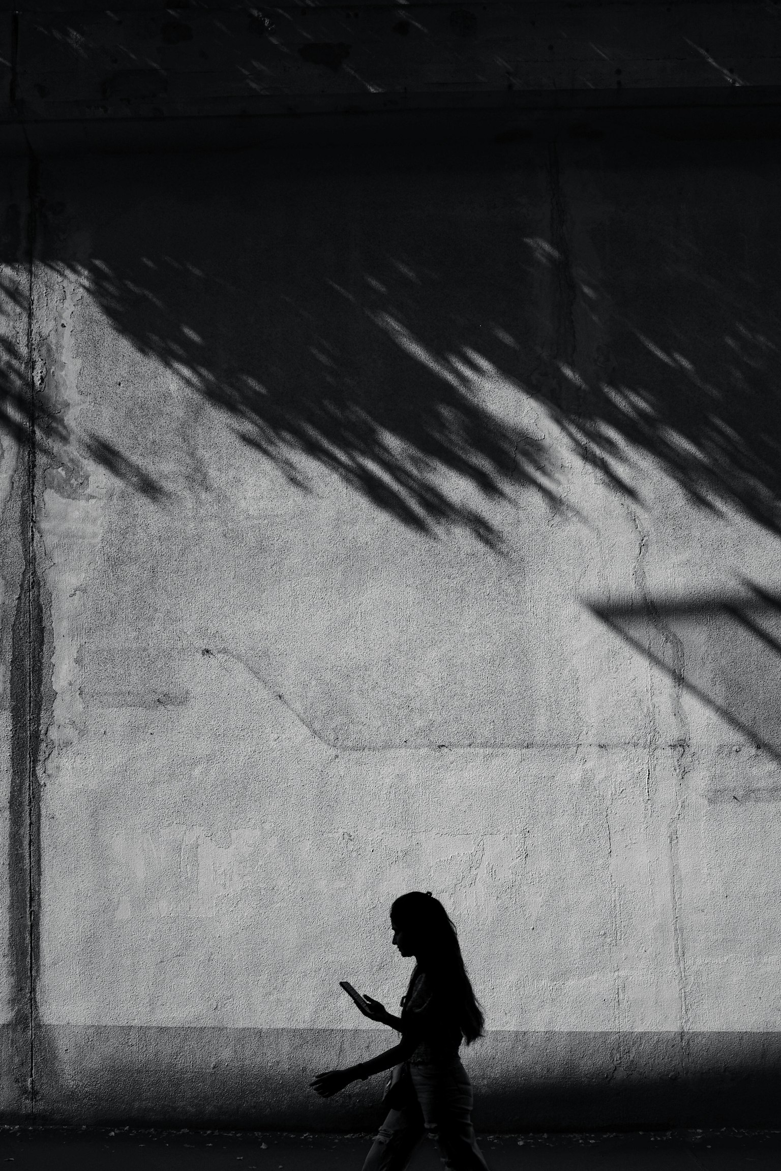 Silhouette einer Frau, die vor einer Wand mit Schatten geht