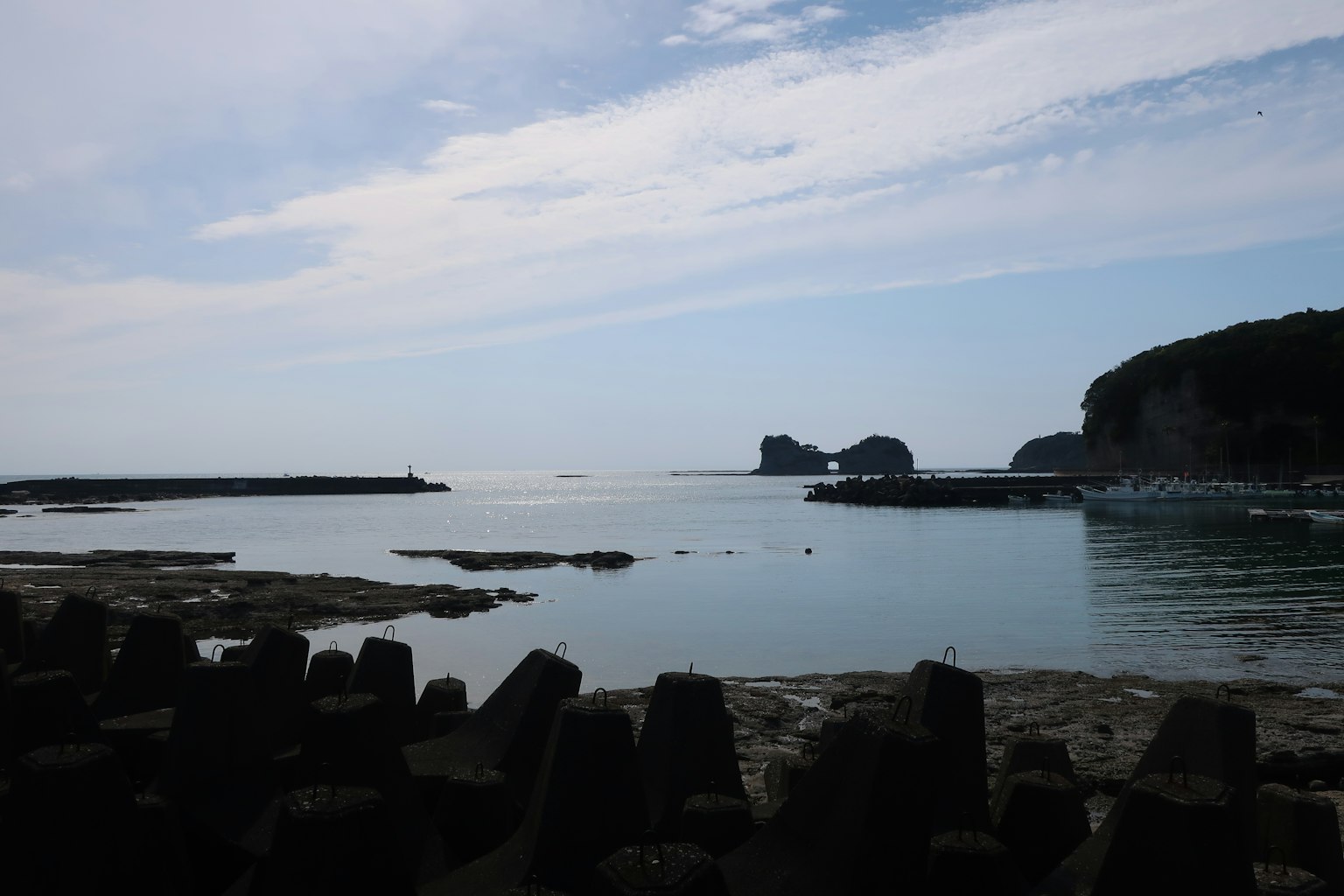 Pemandangan laut tenang dan langit biru dengan garis pantai berbatu yang terlihat