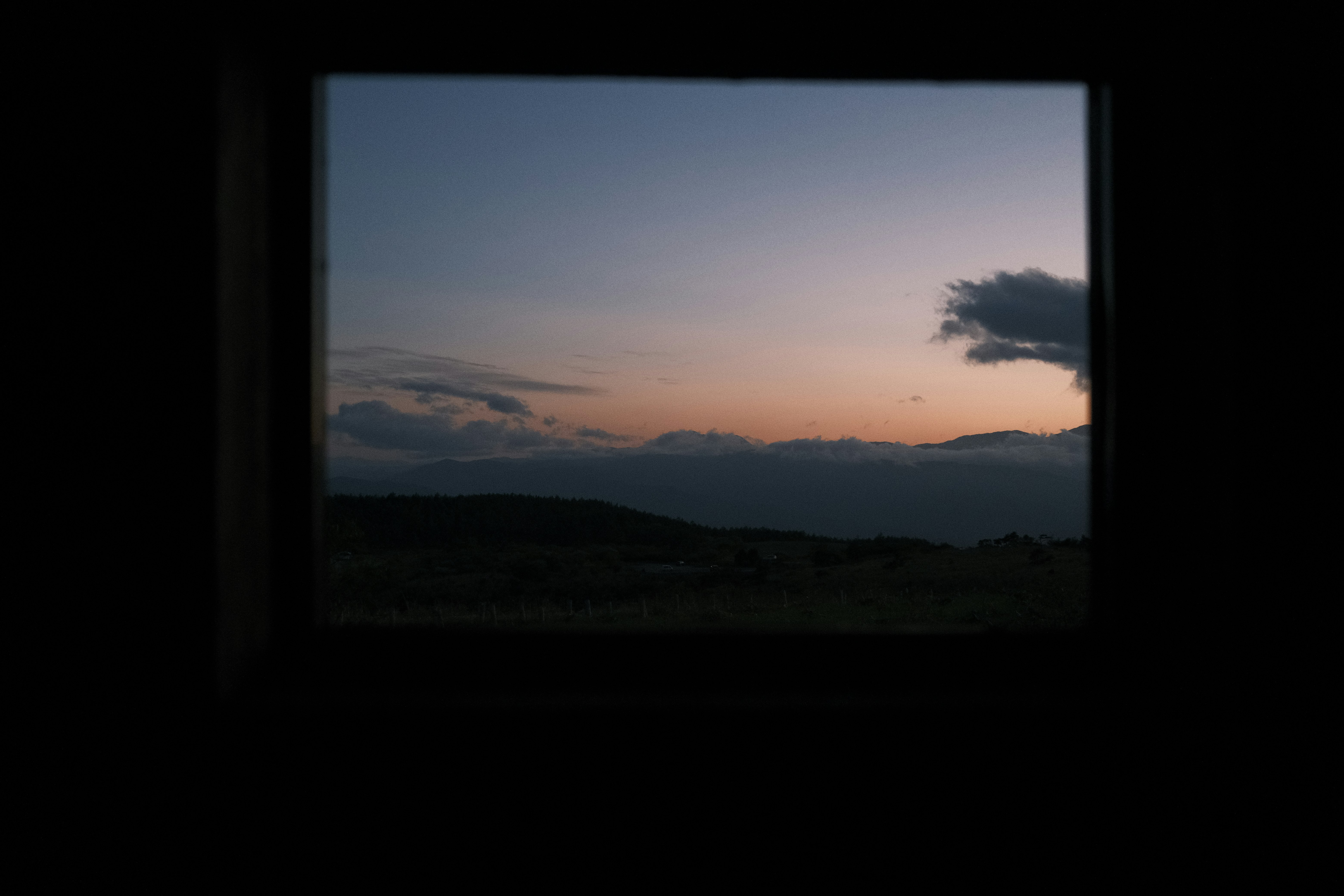 窓枠越しに広がる夕焼けの山並みの風景