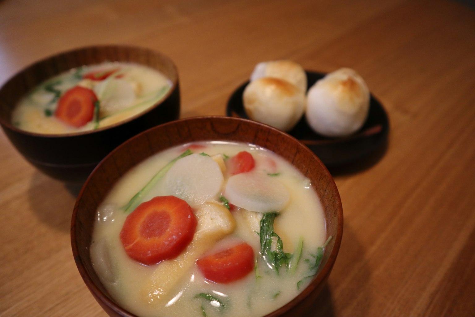 Dua mangkuk sup sayuran dan ayam dengan wortel dan sepiring roti bulat panggang