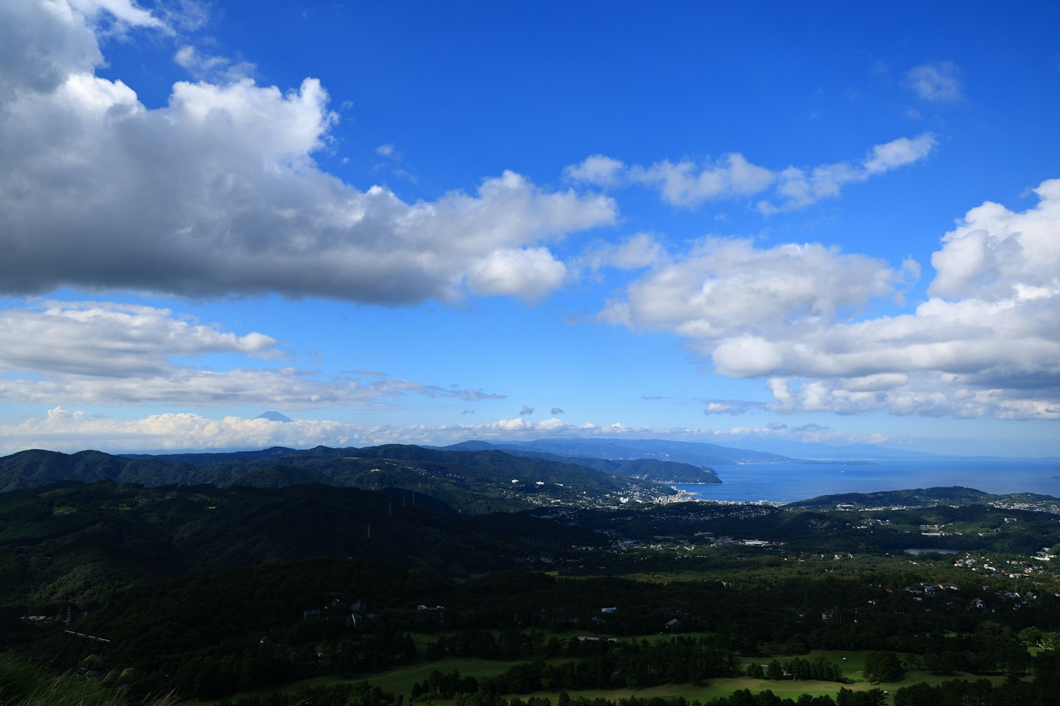 Vista panoramica di montagne e mare sotto un cielo azzurro con nuvole