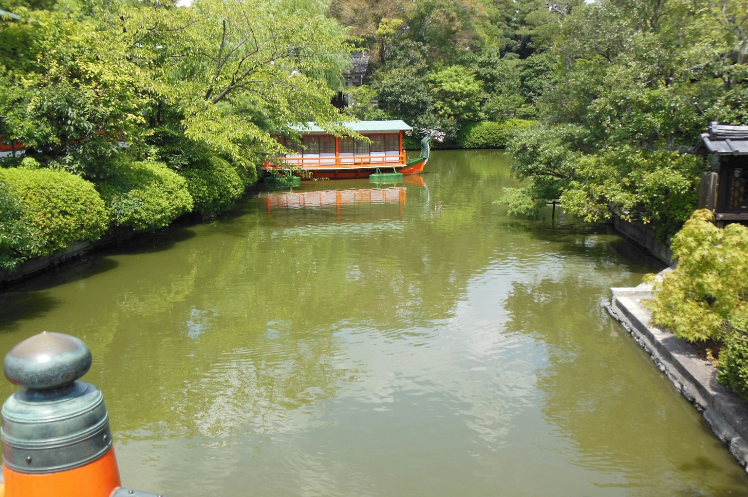 ทิวทัศน์ที่เงียบสงบมีบ่อน้ำสีเขียวและบ้านเรือขนาดเล็ก