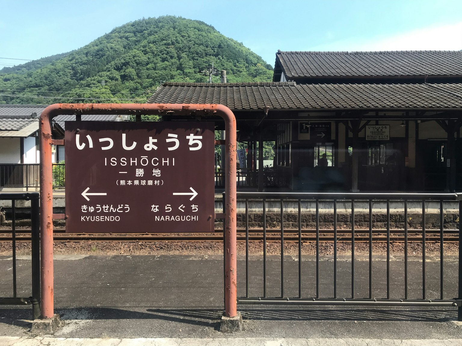 Papan stasiun Ishiochi dengan latar belakang gunung